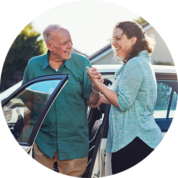 woman helping elderly man out of a car